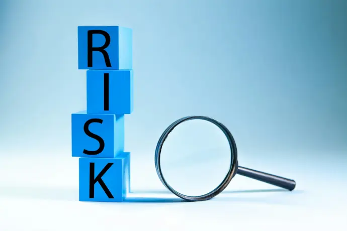 Blue blocks spelling risk next to a magnifying glass